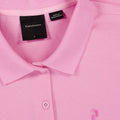 Nahaufnahme eines rosa Peak Performance Poloshirts in Größe S, hergestellt in Bangladesch, mit sichtbarem Kragen, Knöpfen und Marken-Etikett