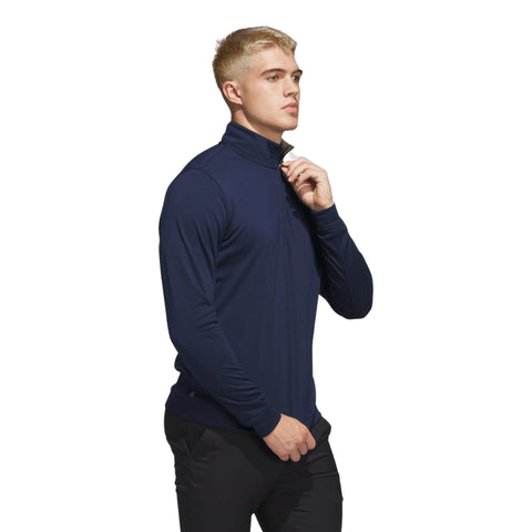 Junger Mann in dunkelblauem Rollkragenpullover und schwarzer Hose vor neutralem Hintergrund