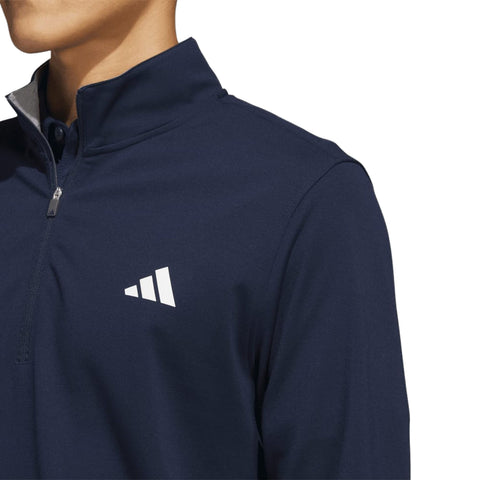 Nahaufnahme eines marineblau-farbenen Adidas Sweatshirts mit halbem Reißverschluss und kleinem weißem Logo