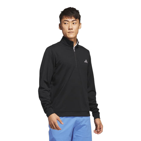 Schwarzer Adidas Herren-Pullover mit halbem Reißverschluss, getragen von einem asiatischen Mann mit blauer Hose